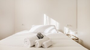 A hotel room with a neatly made bed, a welcome box, and a bedside table with a lamp. - Domus Appia by Rentbeat (Roma)