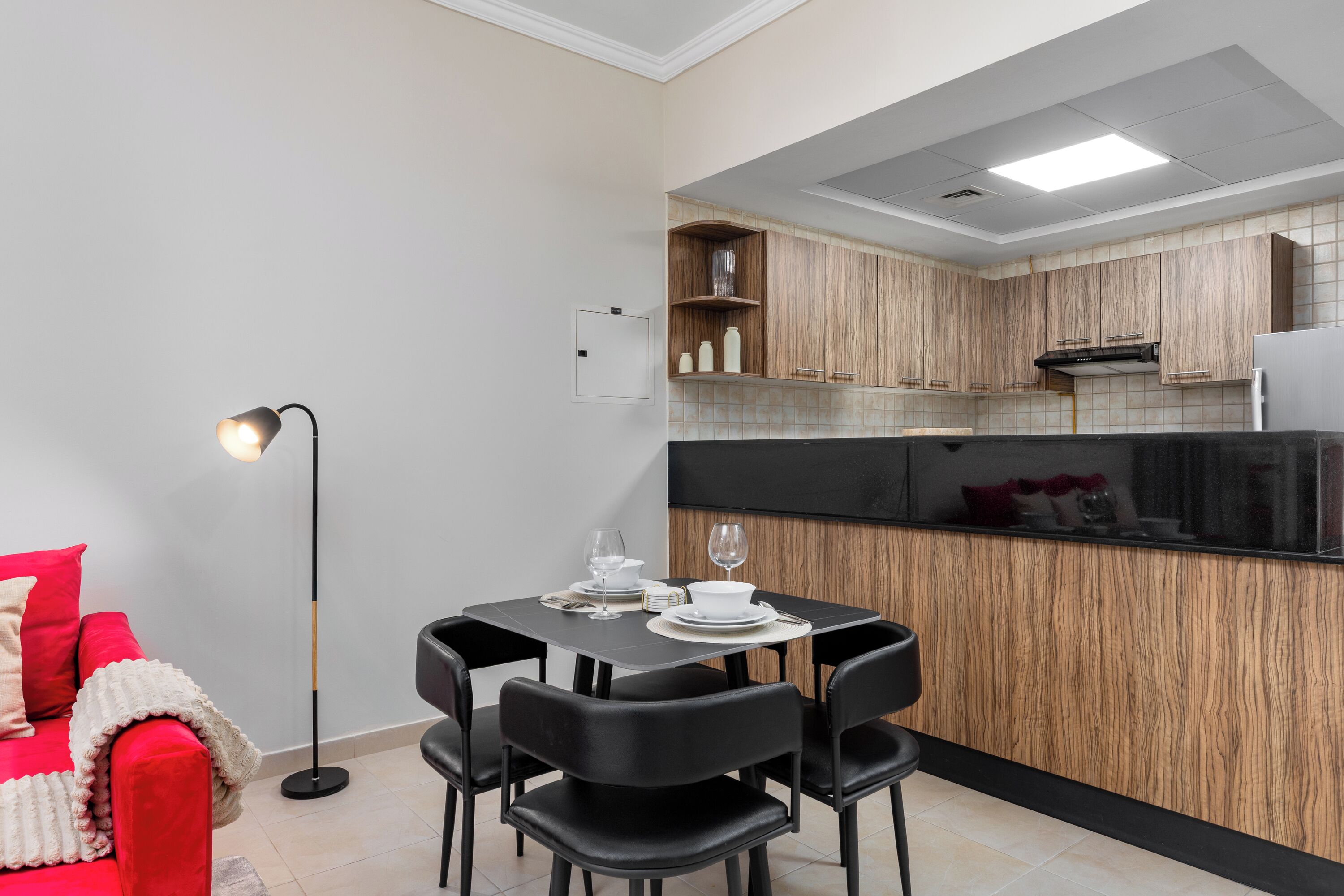 A compact kitchen with wooden cabinets, a black countertop, and a dining area with a table set for two.