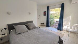Une chambre avec un lit, une chaise, une petite table et une vue sur l’extérieur.