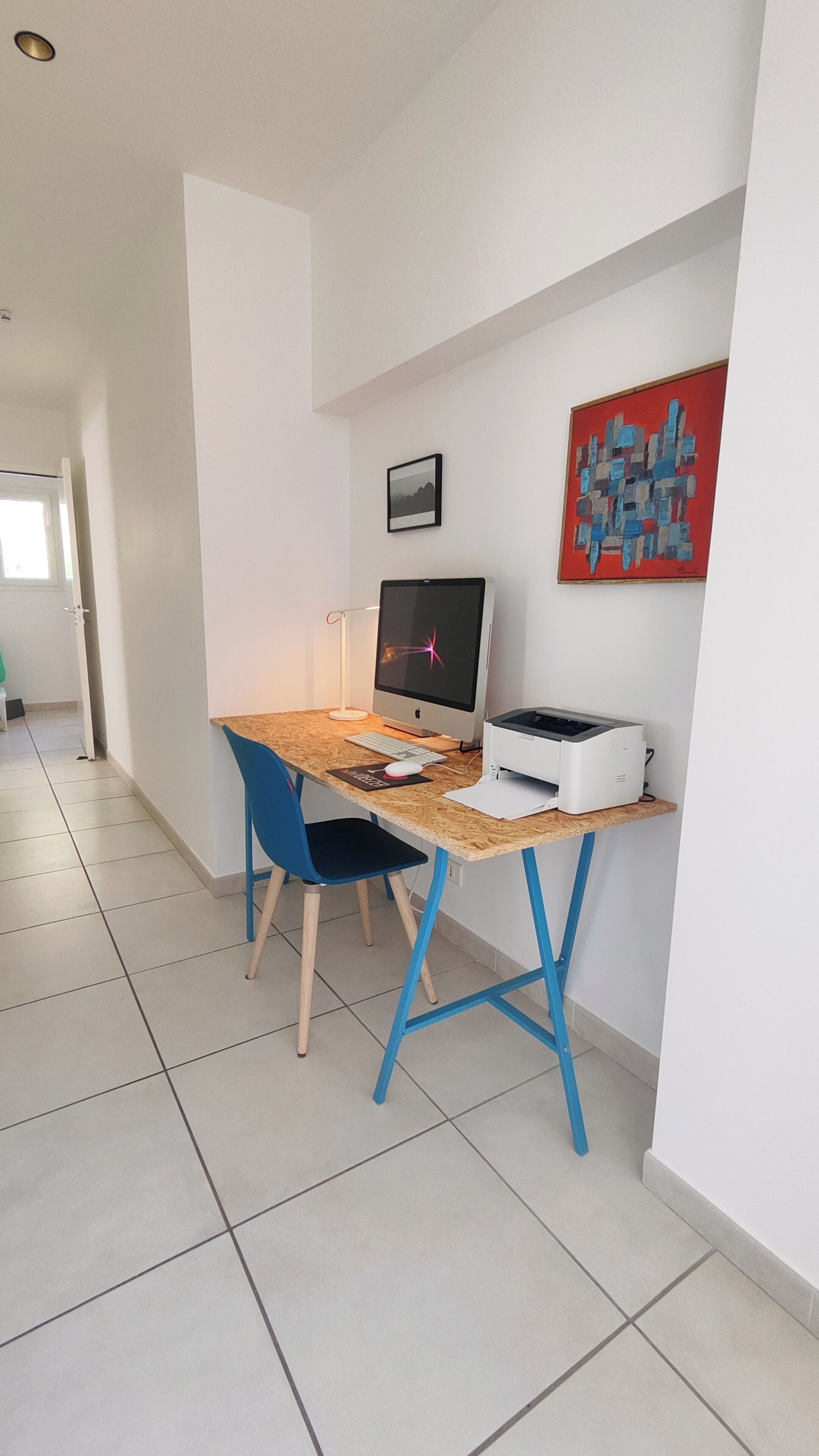 Un espace de bureau moderne comprenant un bureau, un ordinateur, une imprimante et des chaises.