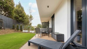 Eine Terrasse mit Liegestuhl, Tisch und Stühlen.