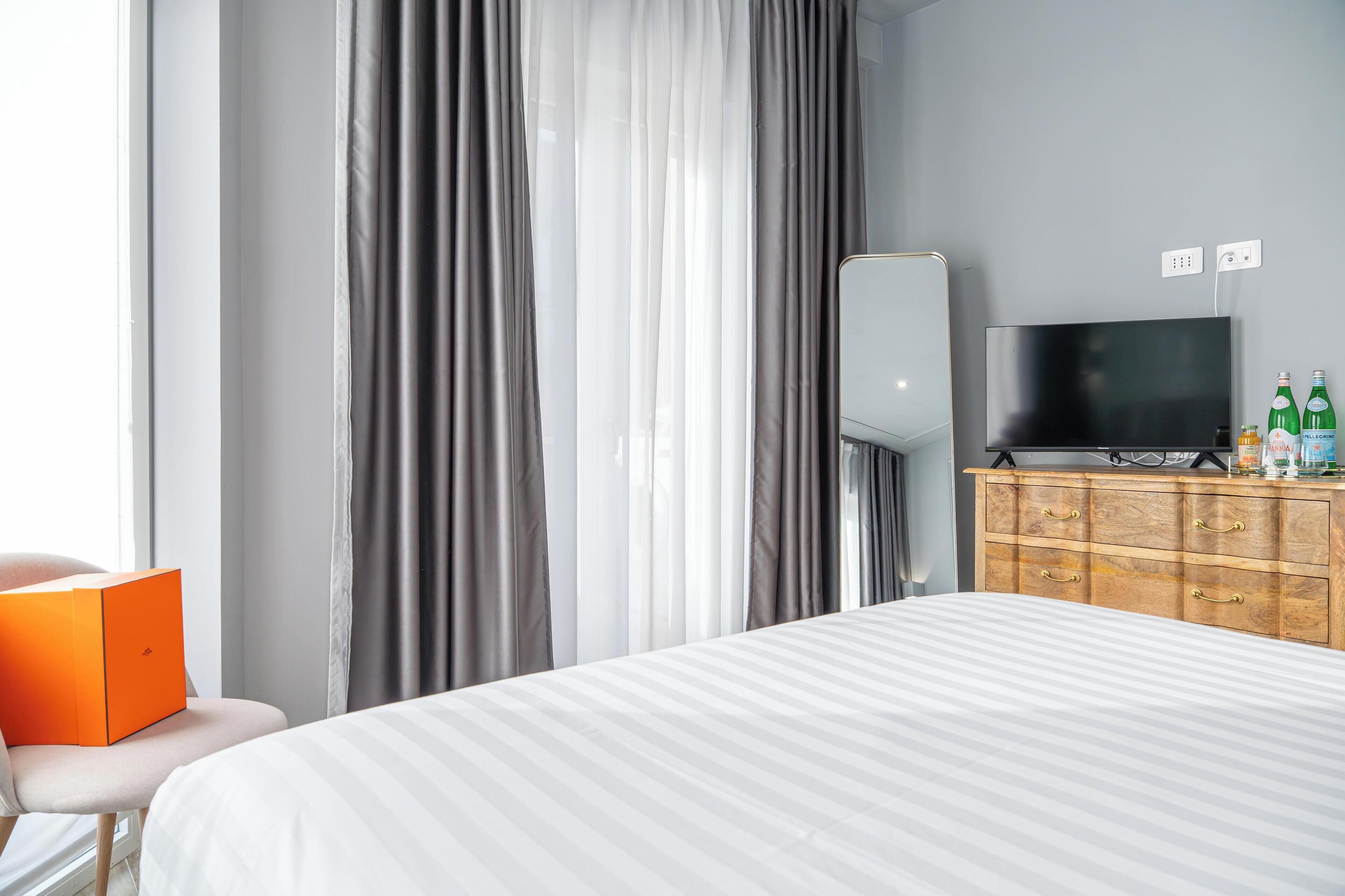 A hotel room with a bed, a TV, a wooden dresser, and a chair.