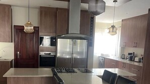A modern kitchen with a central island, stainless steel appliances, and pendant lighting.