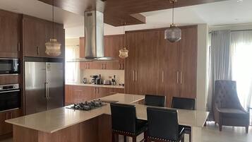 Een moderne keuken met houten kastjes, een centraal eiland en hangende lampen.