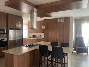 A modern kitchen with wooden cabinets, a central island, and pendant lighting.