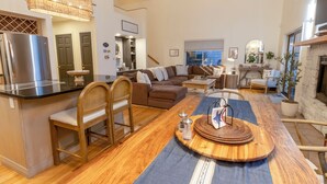 A spacious living area with a wooden dining table, a sofa, and a kitchen area with a refrigerator. - Relaxing Beach Home Near Dunes & Downtown MC (Michigan City)