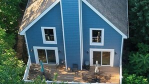 A two-story house with a blue exterior, a chimney, and a deck with outdoor furniture. - Relaxing Beach Home Near Dunes & Downtown MC (Michigan City)