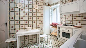 Una cocina con salpicadero de azulejos, armarios blancos, una estufa y un lavamanos.
