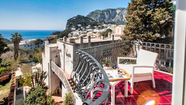Una terraza con mesa y sillas, con vista a un pueblo costero y al mar.