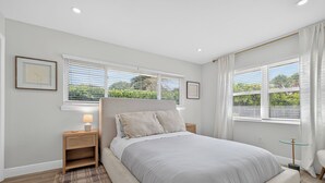 A bedroom with a large bed, two bedside tables, a nightstand, and a window with blinds. - Coral Ridge Suites #1 - Heated Pool, Beach Gear (Fort Lauderdale)