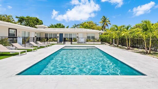 A rectangular swimming pool with a clear blue water surface, surrounded by a white tiled deck. - Coral Ridge Suites #1 - Heated Pool, Beach Gear (Fort Lauderdale)