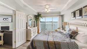 A bedroom with a large bed, a ceiling fan, a view of the sea, and a sign for Ocean City Vacation Homes. - Bahia Vista Unit 201 (Ocean City)
