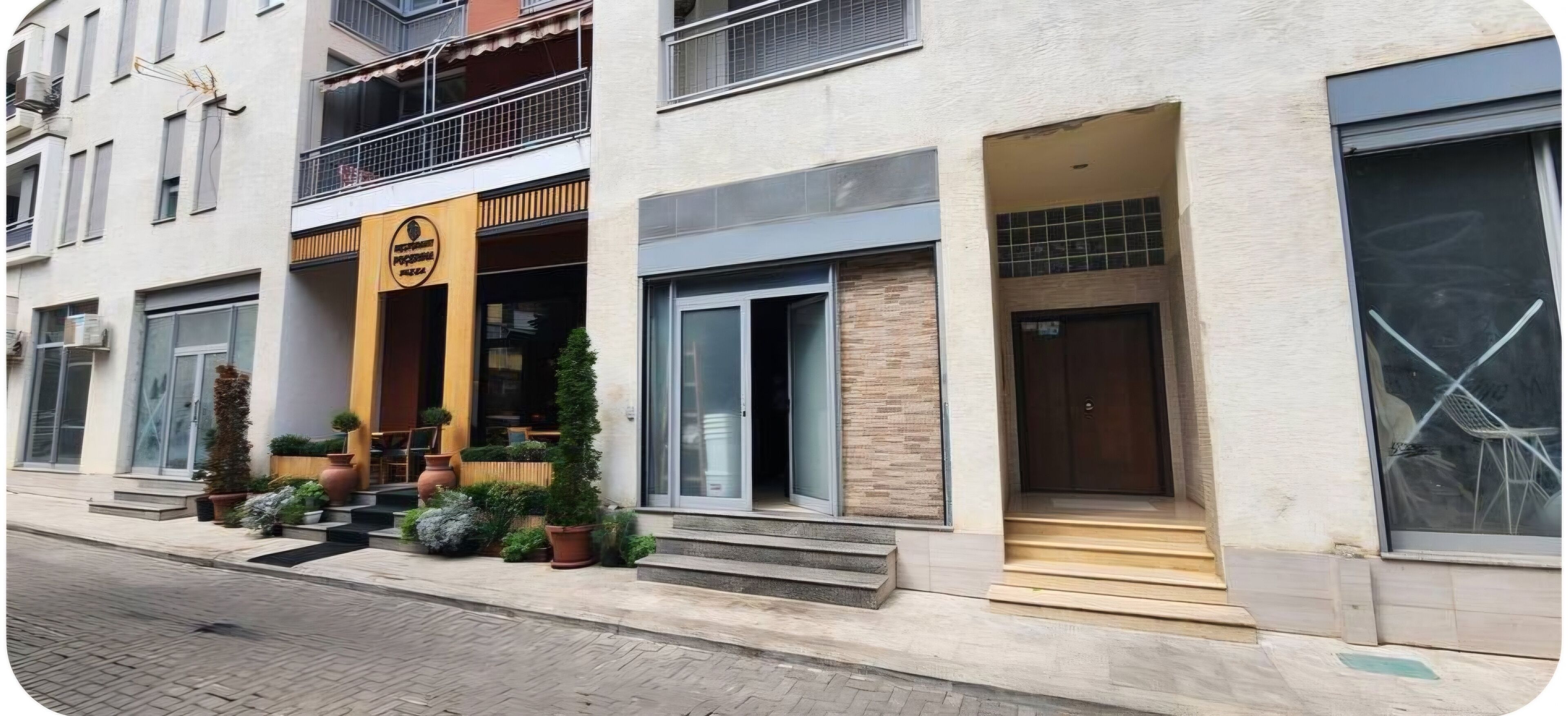 Un edifici modern amb una entrada destacada, grans finestres i un balcó.