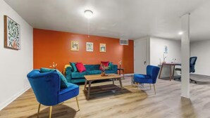 A modern living room with a teal sofa, blue armchairs, and a wooden coffee table. - Cozy 2-BR Home w/ Parking & High-Speed Wi-Fi (Tucker)