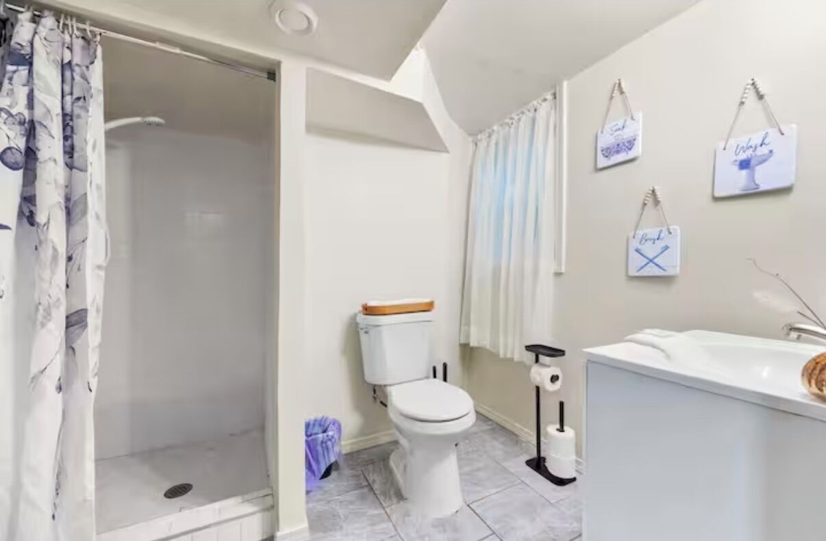 A bathroom with a shower, toilet, and sink.