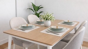Mesa de jantar posta com pratos, talheres e um vaso de flores.