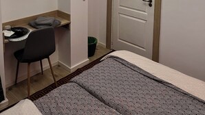 Ein Zimmer mit einem Bett, einem Schreibtisch mit Stuhl, einem an der Wand montierten Fernseher und einer Tür.