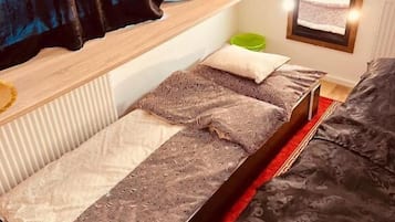 A compact room with a single bed, a small table, and a window with curtains.