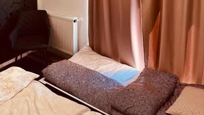 Ein Hotelzimmer mit Bett, Stuhl, Heizkörper und Vorhängen.