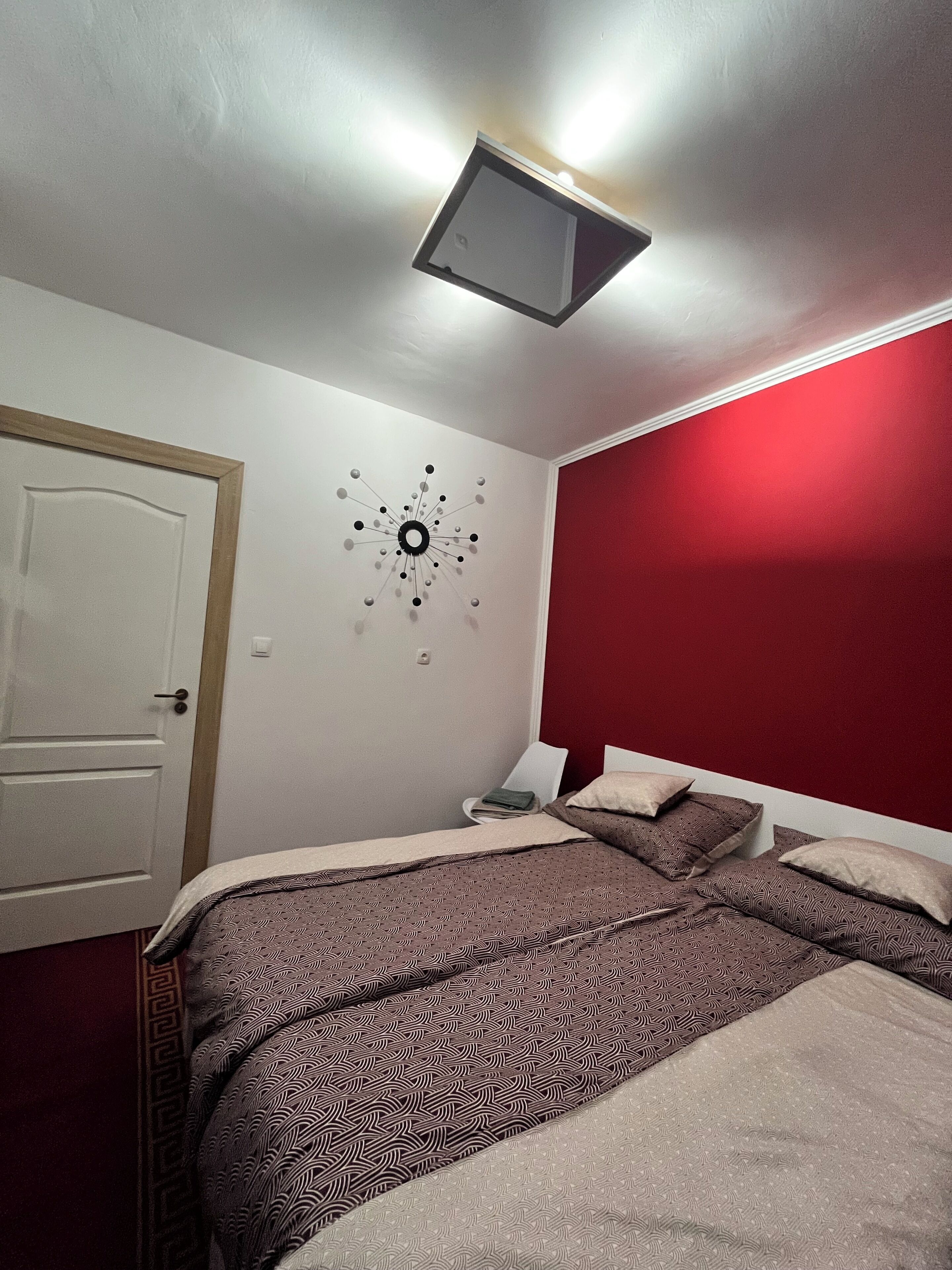 Ein Schlafzimmer mit Bett, Schreibtisch, Stuhl und Wanduhr.