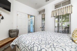 A bedroom with a bed, a bench, a TV, and a door. - Mini Weeks Stays Available Sunset Island 26 Island (Ocean City)
