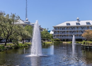 A hotel with a fountain in the courtyard, surrounded by trees and a body of water. - Mini Weeks Stays Available Sunset Island 26 Island (Ocean City)
