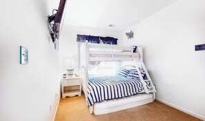 Ein Stockbett mit gestreifter Bettdecke, ein Nachttisch mit Lampe und ein an der Wand befestigtes Regal.