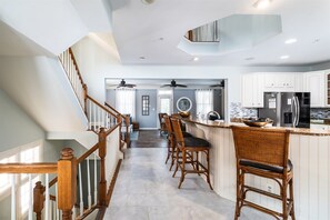 A kitchen with a central island, wooden chairs, and a staircase. - Sunset Island 5 Beachside Mews (Ocean City)