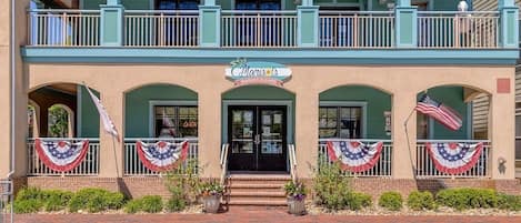 A two-story building with a balcony, a sign reading 'Marie's Market & Cafe,' and American flags.