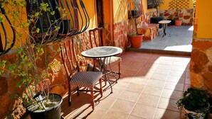 A patio with a table and chairs, a stone wall, and potted plants. - Coco Apart (Vélez-Rubio)