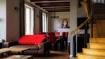 Un interior moderno con escalera de madera, mobiliario de cuero y zona de comedor con sillas rojas.