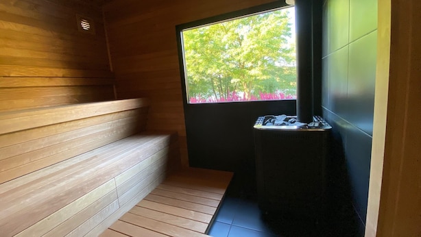Een sauna met houten banken en een raam met uitzicht op bomen en roze bloemen.