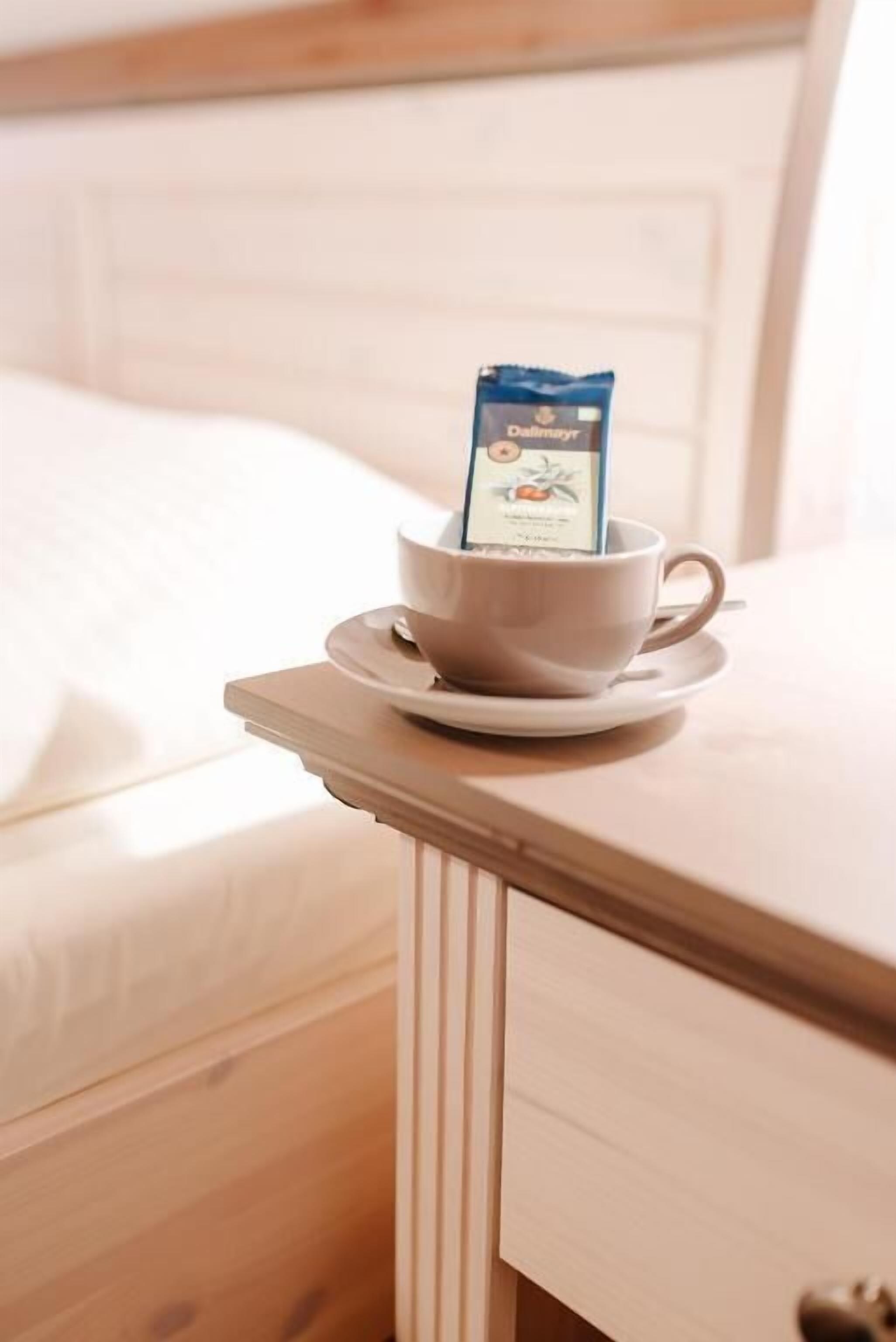Une tasse de café sur une table de chevet, à côté d’une boîte de thé.