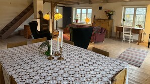 A cozy room with a wooden ceiling, a staircase, a dining table with lace tablecloth, and a sofa. - Charming holiday home in beautiful Österlen |SE01085 (Gärsnäs)