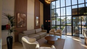 Eine moderne Lobby mit einer Couch, Sesseln, einem Couchtisch und großen Fenstern mit Blick nach außen.