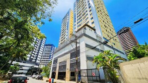 A multi-story building with a modern architectural design, featuring a mix of glass and concrete facades. - Apto c Piscina Academia e Churrasqueira em Pituba (Salvador)