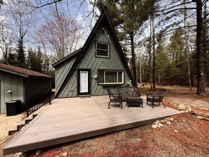 A cabin with a deck, a small porch, and a window.