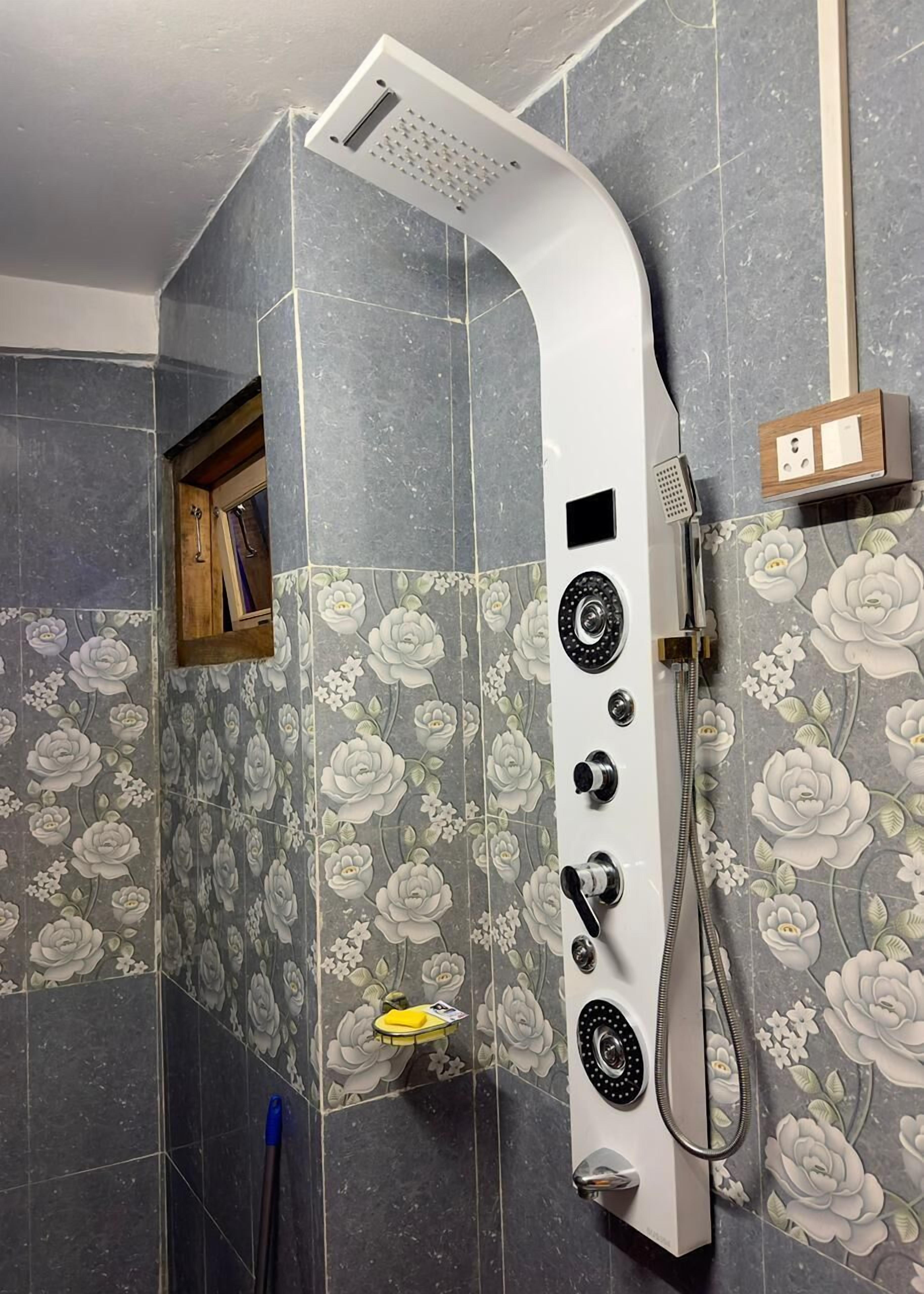 Eine Dusche mit gebogener Form, einer Handbrause und einem Bedienfeld.