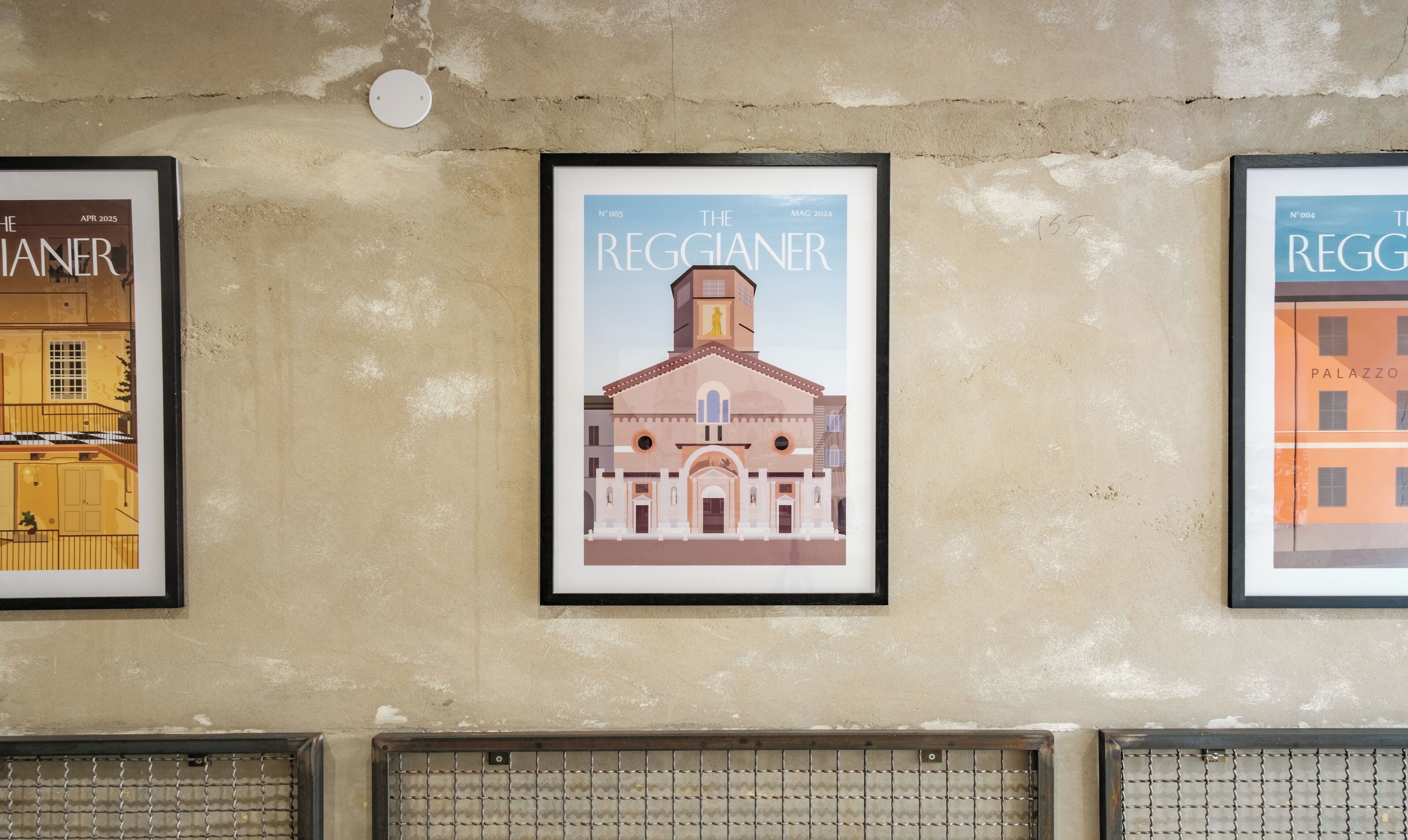 Trois affiches encadrées représentant des bâtiments, accrochées à un mur.