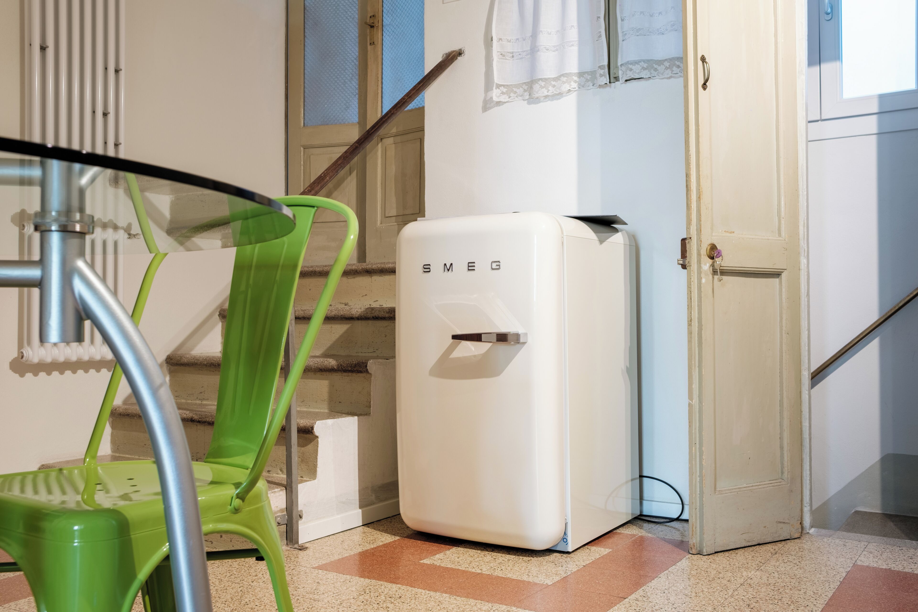 A room with a green chair, a white radiator, and a white wall with a window.