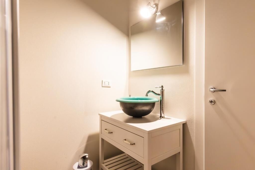 Une petite salle de bain avec un meuble-lavabo blanc, un lavabo vert et un miroir au-dessus.