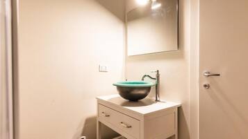 Une petite salle de bain avec un meuble-lavabo blanc, un lavabo vert et un miroir au-dessus.