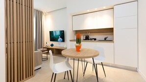 Una cocina moderna con armarios blancos, una mesa de comedor de madera y dos sillas blancas.