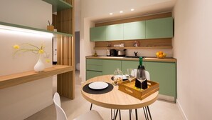 Eine moderne Küche mit grünen Schränken, einem Holztisch und einer Blumenvase.