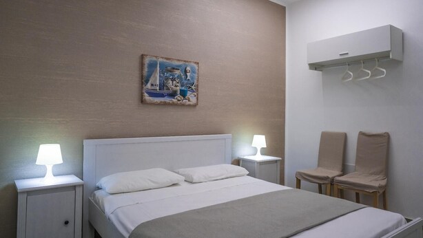 Ein Hotelzimmer mit einem Bett, zwei Nachttischen mit Lampen, einem Sessel und einem Wandbild.