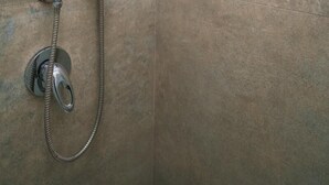 Eine Dusche mit Handbrause und verstellbarem Ventil an der Wand.