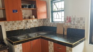 A kitchen with a black countertop, wooden cabinets, a window with bars, and a stove. - Affordable & stylish 1 bedroom Diani Treasured Home, an apartment near the Beach (Diani)