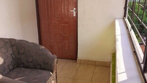 A balcony with a wicker sofa, a wooden door, and a metal railing. - Affordable & stylish 1 bedroom Diani Treasured Home, an apartment near the Beach (Diani)