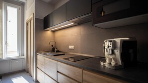 Une cuisine moderne équipée d’une cuisinière intégrée, d’une machine à café et d’une fenêtre laissant entrer la lumière naturelle.