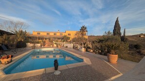 A pool area with a statue, lounge chairs, and a building in the background. - Chestnut Apartment Four Poster (Vélez-Rubio)